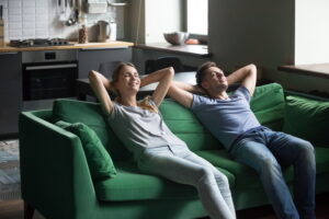 Young man and woman enjoying relaxation taking break for rest at home on comfortable couch, happy couple breathing fresh air meditating leaning on new sofa together, stress free lazy weekend concept