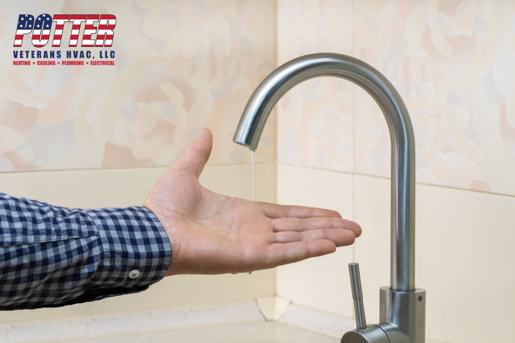 Male hand and faucet with water pouring in a thin steady stream.